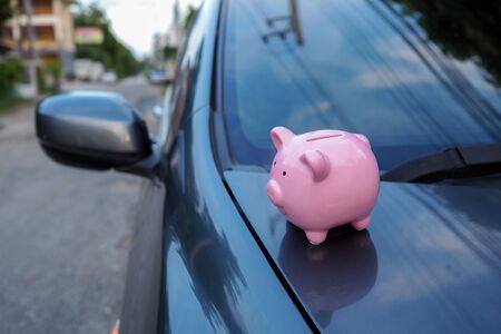 pink piggy bank standing on the car, saving money for new car or saving money with car insurance.の写真素材