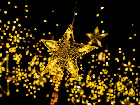 Golden or yellow lighting star are hanging on a black background, It' s a nice party light for this holiday.の写真素材