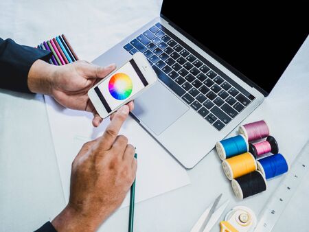 Hand design with Sewing equipment laptop and smartphone on white background.