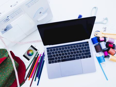 Sewing equipment laptop and smartphone on white background with blank space.
