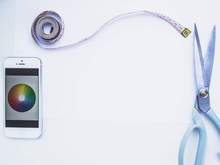 Sewing equipment and smartphone on white background with blank space.
