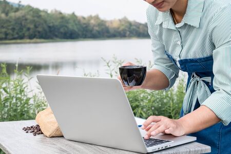 Picture of Business women using laptop note the quality of coffee beans and drinking coffee.の写真素材