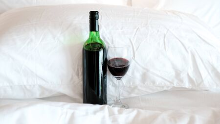 A glass of wine and wine bottle in the bed.の写真素材