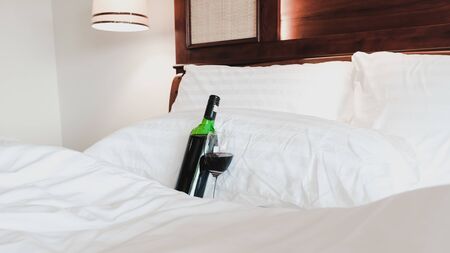 A glass of wine and wine bottle in the bed.の写真素材