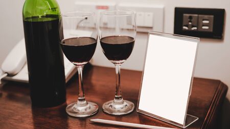 Two glasses of wine and wine bottle with phone on the wooden table.の写真素材