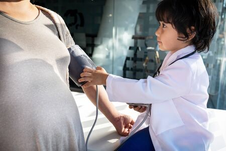 The kid doctor evaluates the patient with a stethoscope, blood pressure monitor.
