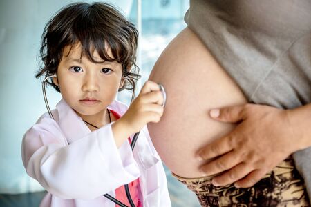 Photo of kid doctor and stethoscope with pregnant mother in the office.