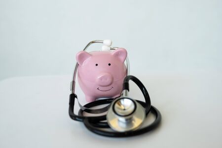 Pink piggy bank with stethoscope on white background, Saving money for future plan and retirement fund concept.の写真素材