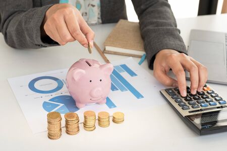 Pink piggy bank with business woman in office, saving for new business target and retirement concept.の写真素材