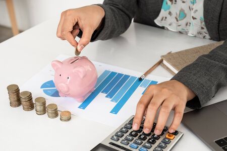 Pink piggy bank with business woman in office, saving for new business target and retirement...