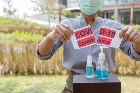 The women hand holding covid19 paper make a symbol fight in disaster covid19, and wearing the mask.の写真素材