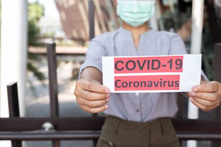 The women hand holding covid19 paper make a symbol fight in disaster covid19, and wearing the mask.の写真素材
