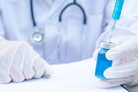 The doctor's hand is holding a blue serum tube and syringe.の写真素材
