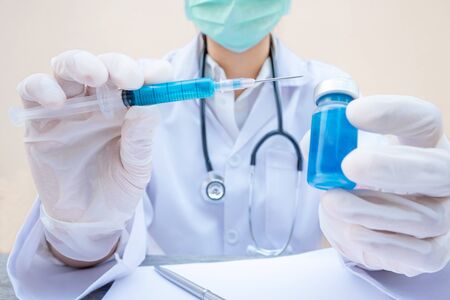 The doctor's hand is holding a blue serum tube and syringe.