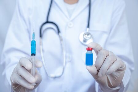 The doctor's hand is holding a blue serum tube and syringe.の写真素材