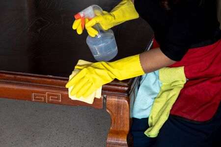 The housekeepers  used cloth and cleaning solution to clean the table and chair.の写真素材