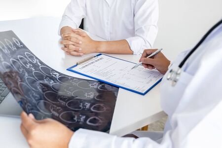 Doctor evaluates the brain X-ray and advise patients on health care.の写真素材