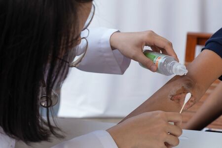 The doctor is treating the wound on the elbow of the patient.の写真素材