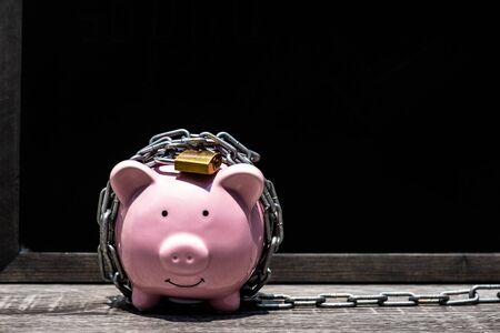 pink Piggy bank locked, chained with black background, Protect savings, Protect capital, Protect retirement fund concept.の写真素材