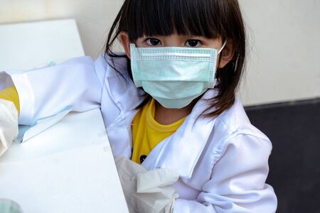 Kid wearing mask wearing gloves is playing a doctor.の写真素材