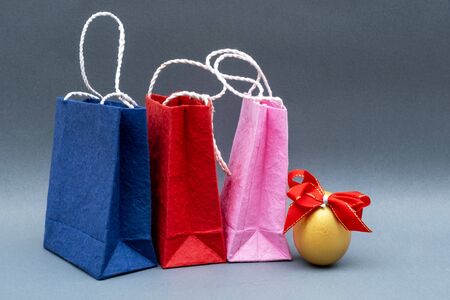 Golden Egg with red Ribbon and shopping bags isolated on gray background.