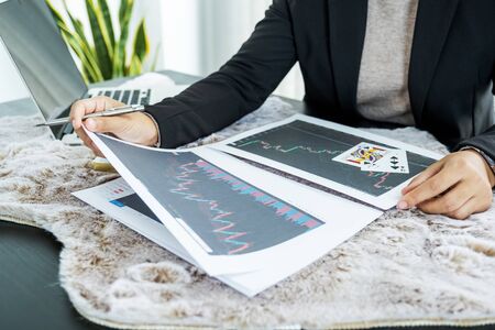 Young businesswomen sitting at a desk with a laptop, stock chart and cards, Don't play stockshare...