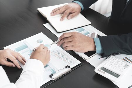 businessmen and businesswomen team pointing to charts meeting to plan strategies to increase...
