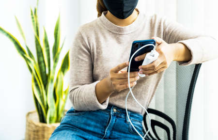 young woman's hand is playing with a smartphone while charging a smartphone battery.