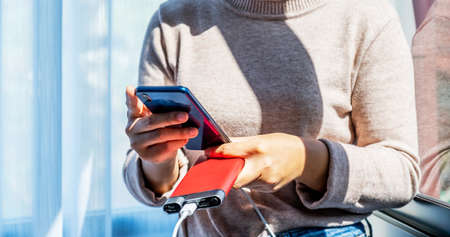 young woman's hand iholdimg smartphone while charging a smartphone battery.の写真素材
