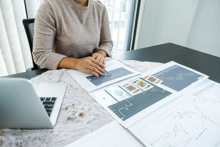 Young women sitting at a desk with a laptop, stock chart and cards, Don't play stockshare like gambling concept.の写真素材