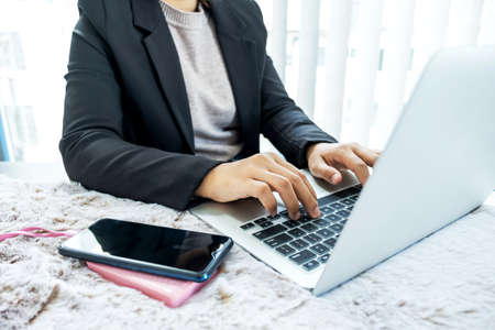 Business women charge mobile phones while sitting at a desk.の写真素材