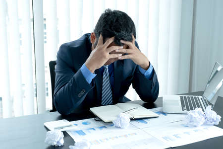 Businessman acted with tired stress anxiety from the frustrated business crisis, paperwork paper cube mess chaos on the table.の写真素材