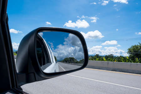 Beautiful clouds and sky landscape from the window of the car on road, reflection on the side mirror...