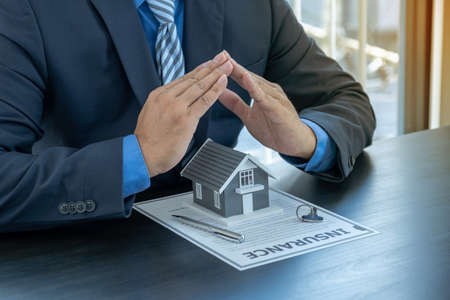 Hand a real estate agent, prevent the home model and explain the business contract, rent, buy, mortgage, loan, or home insurance.の写真素材