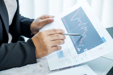 Businesswomen analyze stock graph and report, set targets for online trading management success.の写真素材