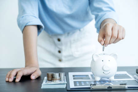 Woman putting coin into piggy bank, step up start up business to success, Saving money for future plan and retirement fund concept.の写真素材