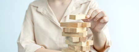 Hand holding blocks wood game, Concept Risk of management and strategy plan, growth business success process and team work.の写真素材