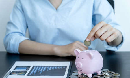 Woman putting coin into piggy bank, step up start up business to success, Saving money for future plan and retirement fund concept.の写真素材