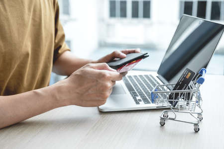 Businessman hand hold credit card to online shopping on laptop computer from home, payment...