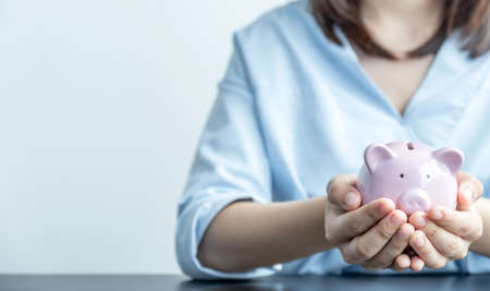 Woman hand holding piggy bank, step up start up business to success, Saving money for future plan and retirement fund concept.の写真素材