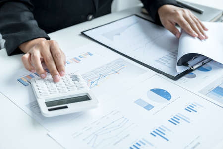 businesswomen bookkeeper use calculator and laptop doing account for paying tax on white desk in...