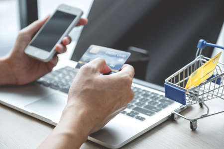 Businessman hand hold credit card to online shopping on laptop computer from home, payment...