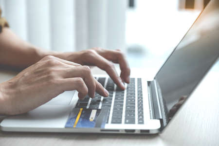 Businessman's hand typing laptop computer  to online shopping with credit card from home, payment e-commerce, internet banking, spending money.の写真素材