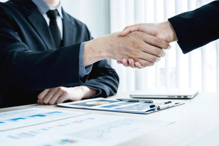 businessmen and businesswomen shacking hands after meeting to plan strategies to increase business income. Have a brainstorming graph analysis and discussing for the new target success.の写真素材