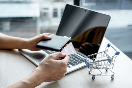 Businessman hand hold credit card to online shopping on laptop computer from home, payment e-commerce, internet banking, spending money.の写真素材