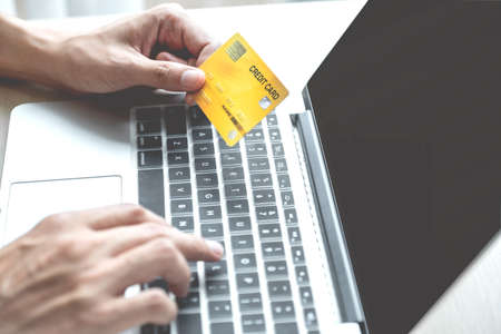 Businessman hand hold credit card to online shopping on laptop computer from home, payment...