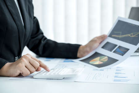 businesswomen bookkeeper use calculator and laptop doing account for paying tax on white desk in...