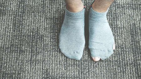 A pair of feet wearing old, dirty, and torn socks.の写真素材