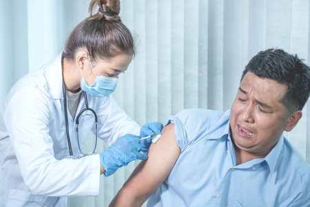 The doctor's hand holding a syringe and was about to vaccinate a patient in the clinic to prevent...