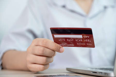 Businesswoman hand hold credit card to online shopping on laptop computer from home, payment...